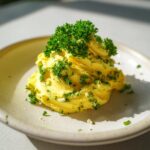 A mound of bright yellow homemade garlic butter mixed with herbs and topped with fresh parsley.