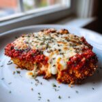 Close-up of a perfectly baked piece of chicken parmesan recipe, topped with melted mozzarella and marinara sauce.