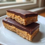 Two rectangular buckeye graham crackers bars stacked, showing a crumbly base, peanut butter filling, and chocolate topping.