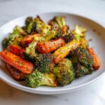Close-up of perfectly caramelized roasted vegetables, featuring bright orange carrots and charred broccoli florets.