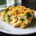 A close-up serving of creamy chicken broccoli rice casserole topped with melted cheddar cheese and crispy breadcrumbs.
