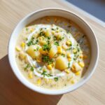 Top-down view of a bowl filled with creamy corn chowder, featuring chunks of potato, corn kernels, and parsley garnish.