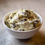 Close-up of a thick, creamy olive dip studded with dark olive pieces, served in a white bowl.
