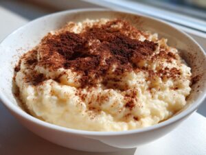 Close-up of a bowl of creamy rice pudding generously dusted with cocoa powder.