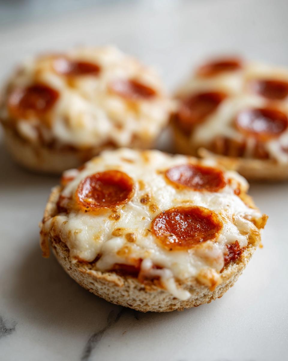 Close-up of a finished english muffin pizza topped with melted mozzarella cheese and pepperoni slices.