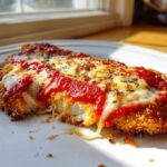 Close-up of a crispy Easy Chicken Parmesan topped with melted mozzarella and bright red marinara sauce.