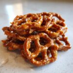 A small pile of shiny, glazed toffee pretzels resting on a light countertop.