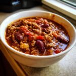 Close-up of a white bowl filled with rich, hearty high protein chili featuring ground meat and kidney beans.
