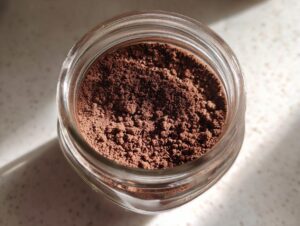 Overhead view of rich brown homemade hot cocoa mix powder stored in a clear glass jar.