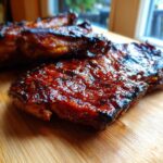 Close-up of a juicy, glazed pork steak recipe cut, resting on a wooden cutting board.