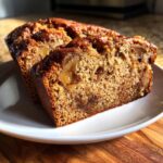 Close-up of two moist slices of homemade apple bread showing tender crumb and chunks of caramelized apple.