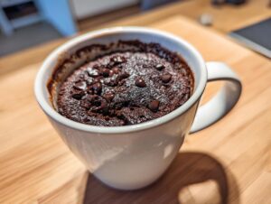 Close-up of a rich, dark chocolate mug cake topped with chocolate chips, ready to eat.