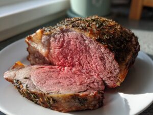 Close-up of a perfectly cooked prime rib recipe roast, showing a medium-rare pink center and herb crust.