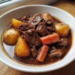 A close-up of tender beef chunks, potatoes, and carrots in a rich gravy from the crockpot beef stew.