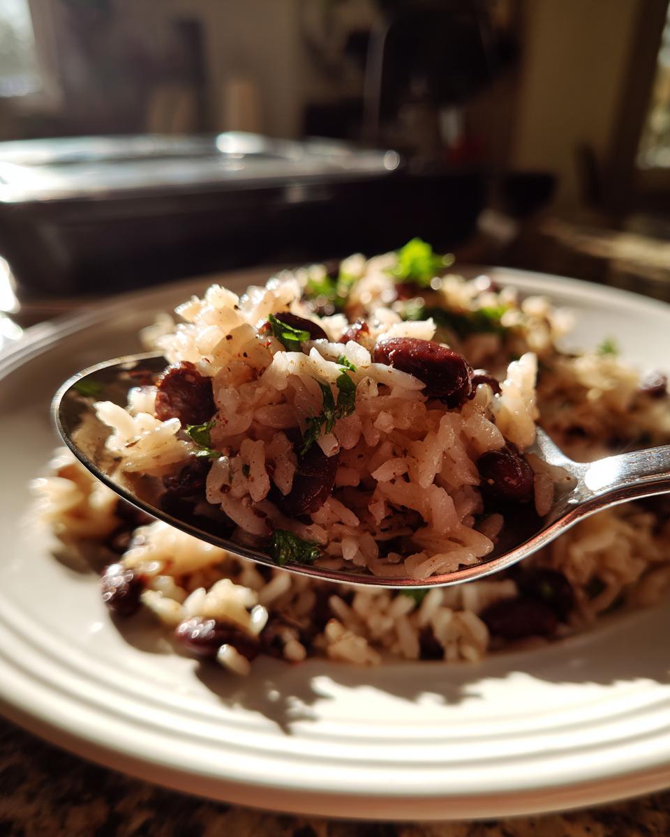 Close-up of a spoonful of flavorful black beans and rice garnished with herbs, highlighted by sunlight.