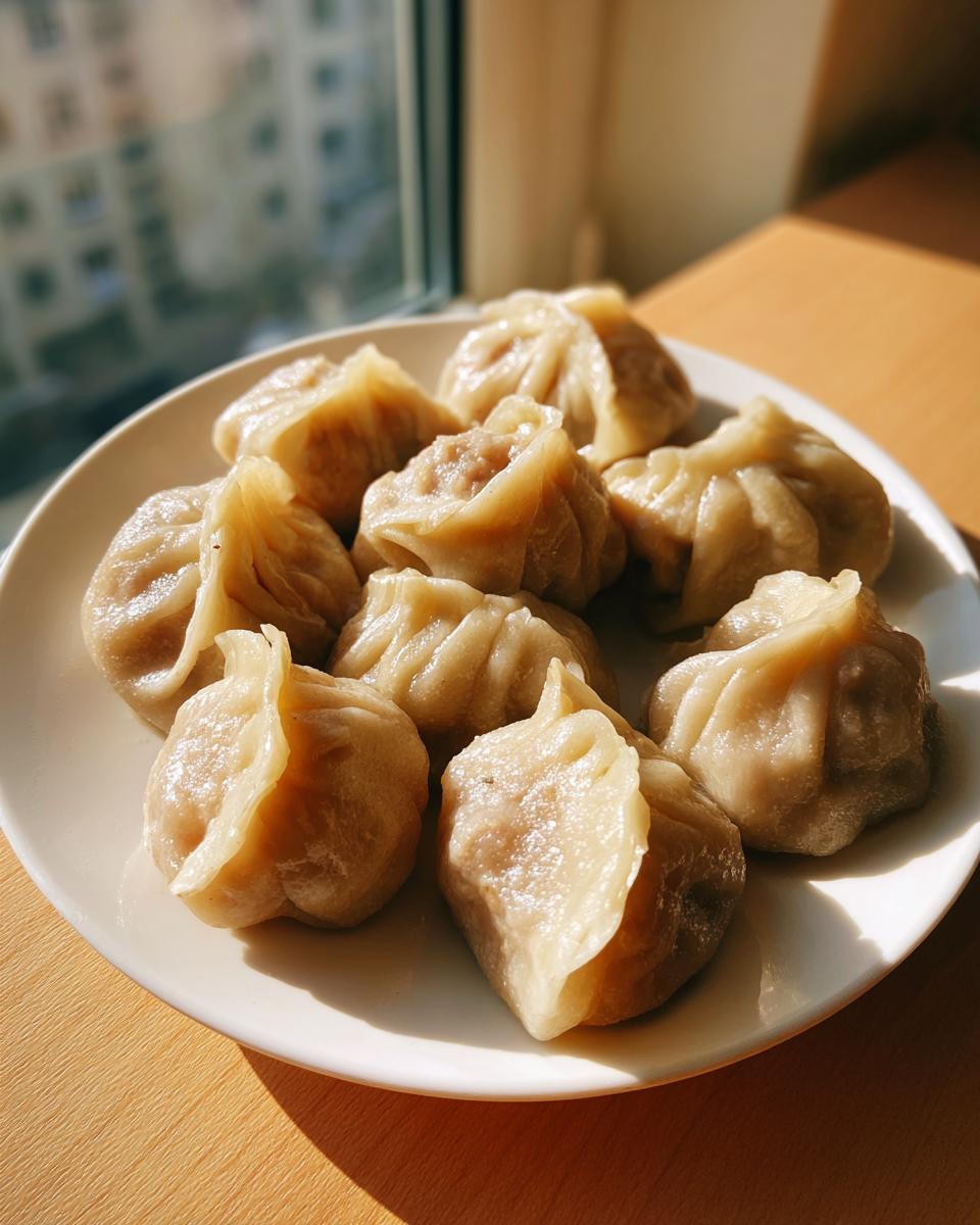 A plate of freshly steamed Traditional Chinese Dumplings resting on a wooden surface near a window.