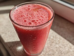 Close-up of a frosty glass filled with a vibrant pink watermelon smoothie, showing condensation droplets.