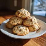 A stack of freshly baked cannoli cookies piled high on a white plate, showcasing their textured tops.