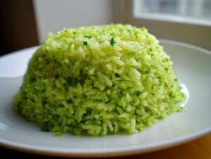 A perfectly molded mound of bright green cilantro lime rice garnished with chopped cilantro on a white plate.