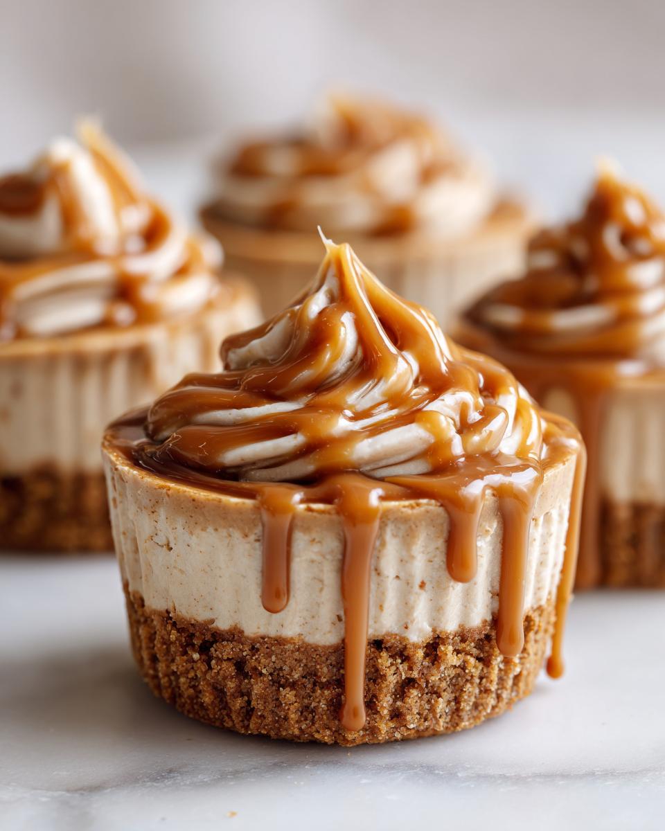 A close-up of one of the cookie butter cheesecake cups topped with whipped cream and a generous caramel drizzle.