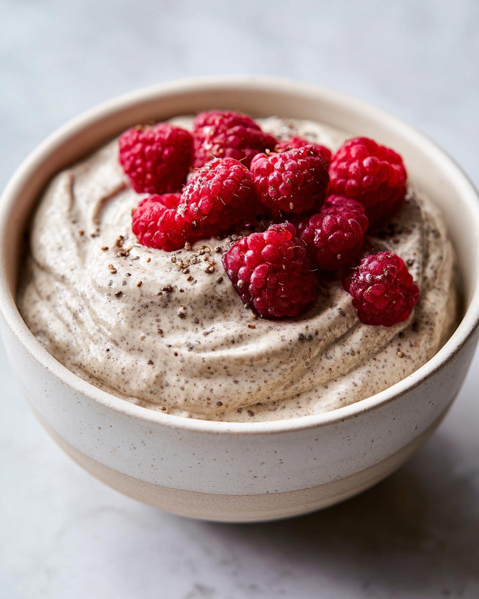 Close-up of creamy chia seed pudding topped with fresh raspberries and sprinkled chia seeds.