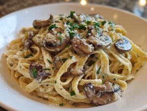 Close-up of creamy mushroom pasta featuring fettuccine noodles, sliced mushrooms, and parsley garnish.