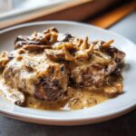 Two pieces of seared meat smothered in a rich, creamy mushroom sauce, showcasing the texture of the mushroom sauce.