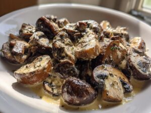 Close-up of sautéed mushrooms coated in a rich, creamy mushroom sauce and sprinkled with herbs.