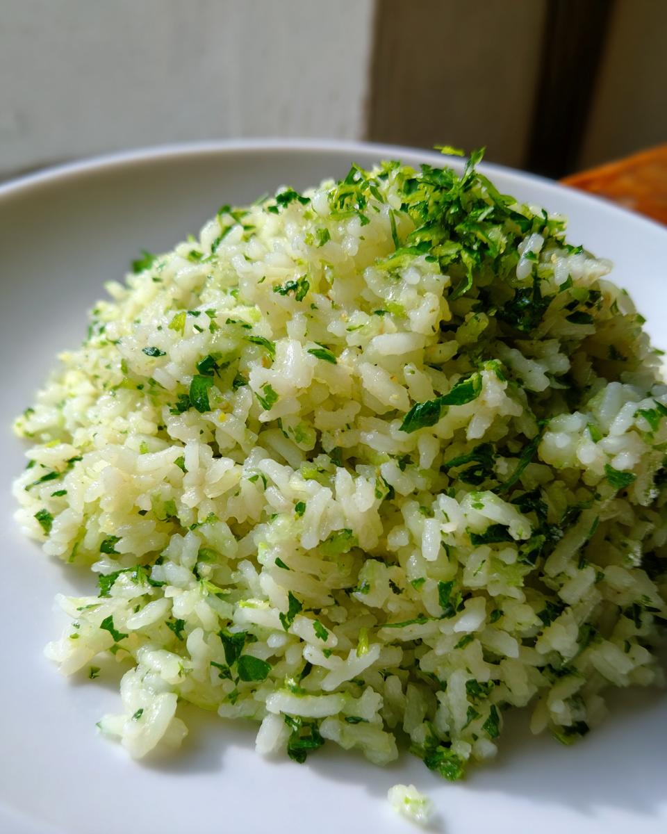 Close-up of fluffy white rice mixed with bright green cilantro and lime zest, served in a white bowl.