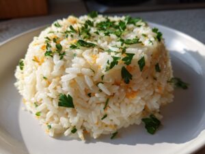 A perfectly molded mound of fluffy white rice pilaf topped with fresh green parsley.