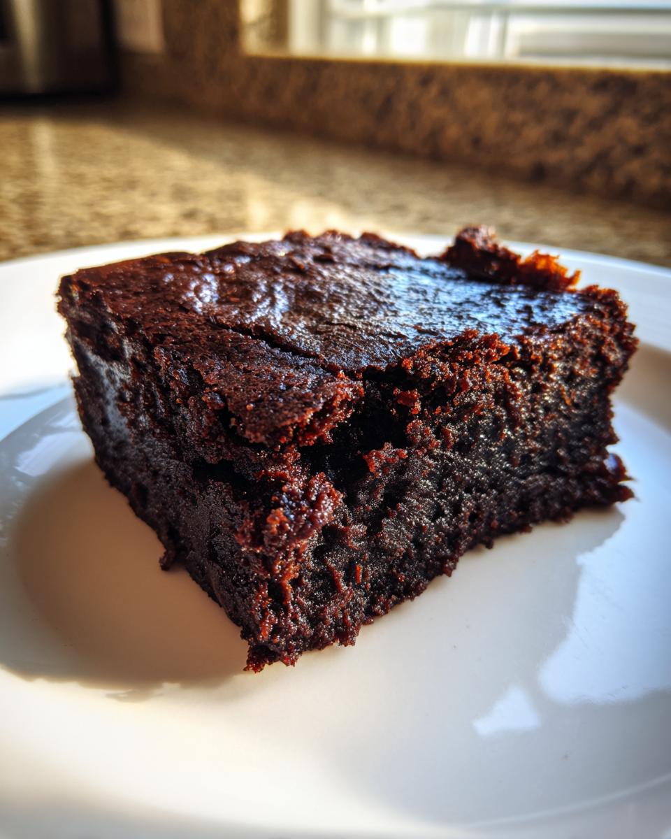 Close-up of a single, rich, fudgy slice of date brownies resting on a white plate.