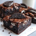 A close-up of fudgy, dark chocolate oreo brownies, topped with a half Oreo cookie.