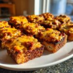 Close-up of several toasted bread squares topped with savory meat mixture and melted cheddar cheese, ready to serve as a hanky panky recipe appetizer.