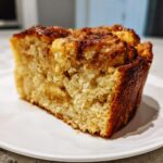Close-up of a moist slice of amazing bread pudding with a caramelized top, served on a white plate.