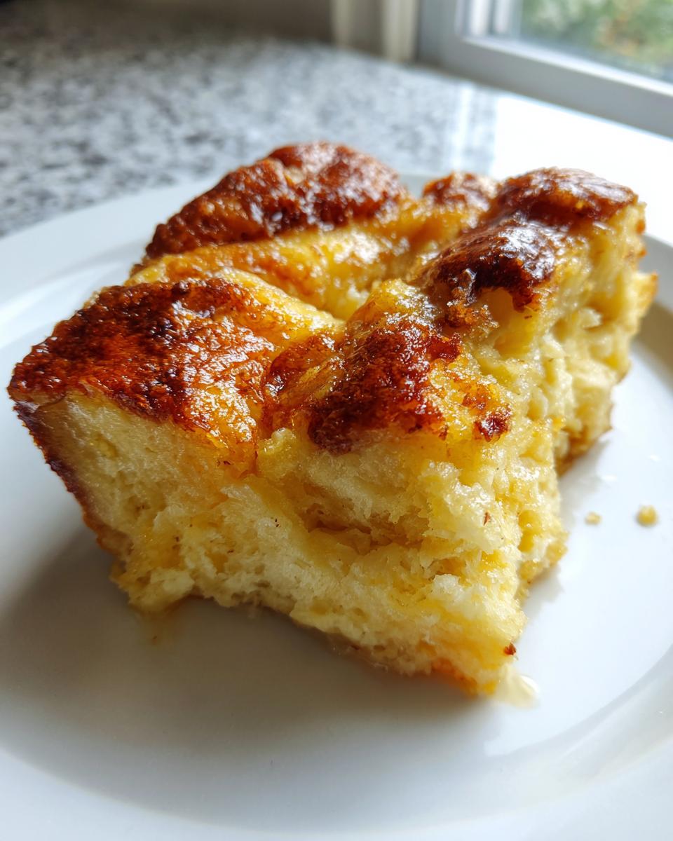 Close-up of a moist, golden-brown slice of amazing bread pudding served on a white plate.