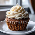 A single, perfectly baked gingerbread cupcake topped with a swirl of thick, creamy white frosting.