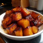 Close-up of perfectly caramelized and slightly charred roasted butternut squash cubes in a white bowl.