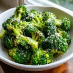 Close-up of bright green steamed broccoli florets topped generously with grated Parmesan cheese.