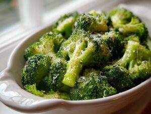 Close-up of bright green steamed broccoli florets topped with grated Parmesan cheese.